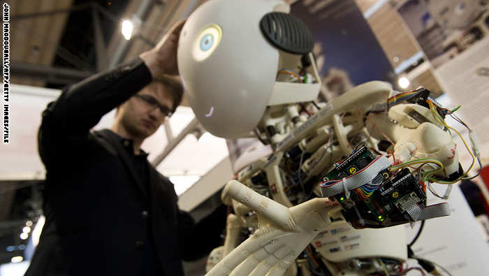 أحد المهندسين ينظر الي روبوت يعمل بتكنولوجيا الذكاء الأصطناعي