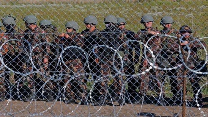 حائط من الاسلاك الشائكة ومن وراءه الجيش المجري في مواجهة المهاجرين