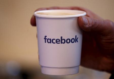 رجل يمسك بكوب مطبوع عليه شعار فيسبوك في برلين يوم 24 فبراير  2016