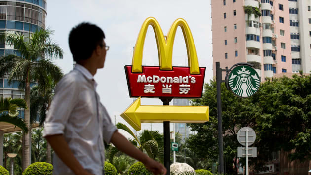 أحد المشاة يمشي بجوار لافتات ماكدونالدز وستاربكس في حي فوتيان في شنتشن، الصين