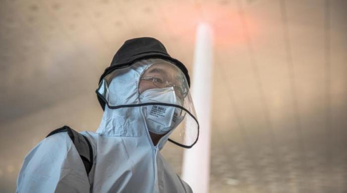 شخص يرتدى قناع وجه أثناء انتظاره في مطار ووهان تيانخه الدولي بعد رفع الإغلاق عن المدينة