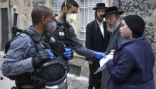 ضباط شرطة إسرائيليون يرتدون قفازات واقية وأقنعة يفحصون الأوراق وهم يفرضون قيودًا في حي يهودي متشدد في القدس يوم الثلاثاء 31 مارس، خلال إغلاق جزئي للحد من انتشار عدوى فيروسات كورونا