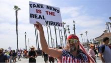 متظاهر يحمل لافتة تشكك في وجود فيروس كورونا في مظاهرة في كاليفورنيا