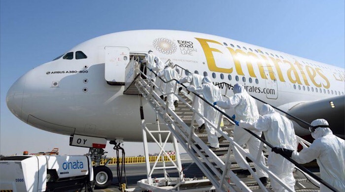 عمال نظافة يرتدون بدلات واقية يصعدون على متن طائرة تابعة لمجموعة الإمارات لتطهيرها في دبي يوم الخامس من مارس ٢٠٢٠