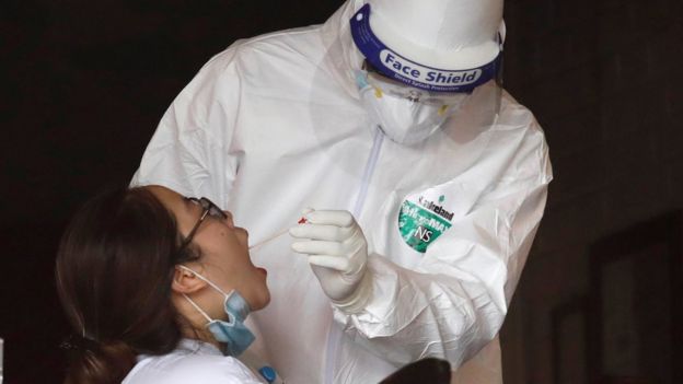 عنصر من الفرق الطبية يقوم بأخذ مسحة من مواطنة للكشف عن فيروس كورونا