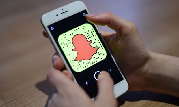 شخص يحمل موبايل يعرض تطبيق سناب شات