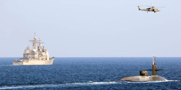 طائرة هليكوبتر من طراز سي هوك تحلق فوق غواصة الصواريخ الموجهة يو إس إس جورجيا، من طراز أوهايو وطراد الصواريخ  يو إس إس بورت رويال، أثناء عبورهما مضيق هرمز، 21 ديسمبر 2020