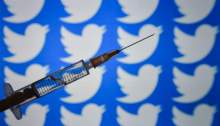 حقنة تحتوي علي لقاح كورونا أمام خلفية لشعار تويتر