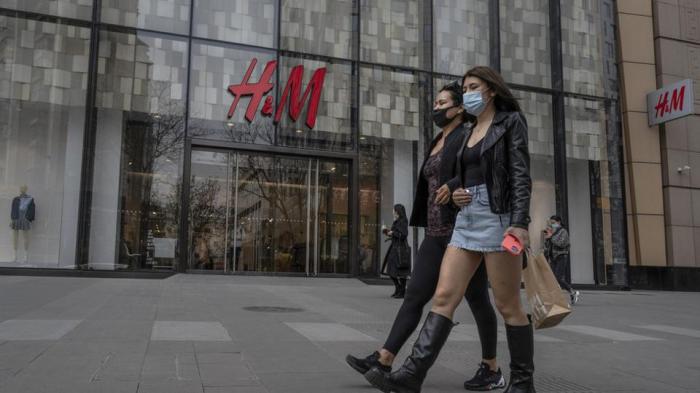 نساء يمشين بجوار متجر ملابس H&M في منطقة تسوق في بكين ، الصين