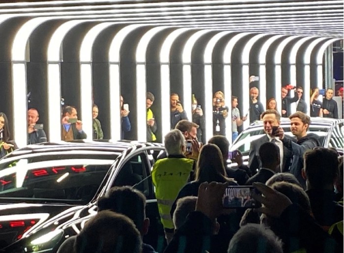 أشخاص يلتقطون صوراً لإيلون ماسك خلال حفل تسليم داخل مصنع تسلا جيجا الجديد للسيارات الكهربائية في جرونهايده، ألمانيا، 22 مارس 2022