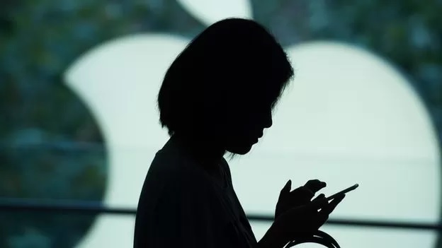 إحدى مستخدمات أيفون تقف خلف شعار أبل