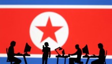 صور مصغرة لأشخاص يحملون أجهزة كمبيوتر أمام علم كوريا الشمالية في هذا الرسم التوضيحي الذي تم تصميمه في 19 يوليو 2023