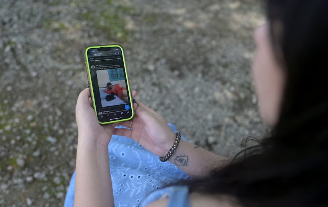 جولي يوكاري، موسيقية مقيمة في ريو دي جانيرو، تحمل هاتفها المحمول الذي يعرض صورة لها أثناء مقابلة، بعد أن اكتشفت أن جروك، روبوت الدردشة المدمج في منصة التواصل الاجتماعي X التابعة لإيلون ماسك، قد أنشأ صوراً شبه عارية لها عندما طلب المستخدمون تعديل صورة نشرتها، في ريو كلارو، ولاية ريو دي جانيرو، البرازيل، 3 يناير 2026