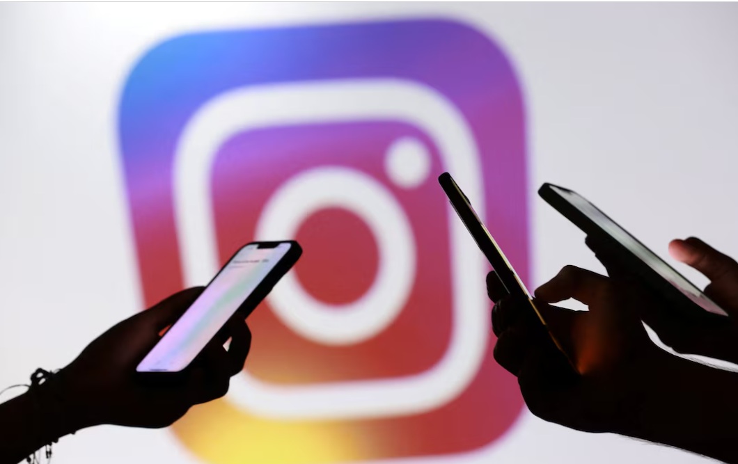مراهقون يقفون لالتقاط صورة وهم يحملون هواتفهم الذكية أمام شعار إنستجرام في هذه الصورة التوضيحية التي التقطت في 11 سبتمبر 2025